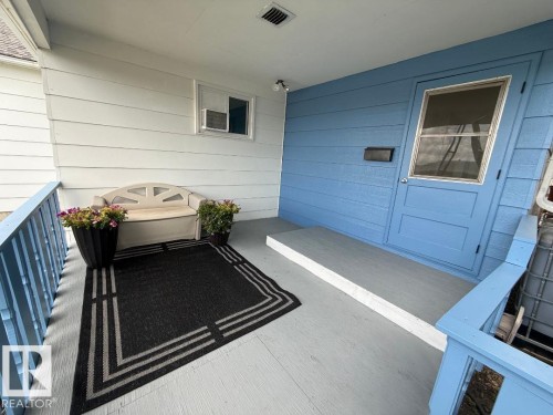 Covered front porch with light blue siding, painted porch flooring, and light blue railings - 4917 45 Avenue, Vegreville, AB - Outdoor With Exterior