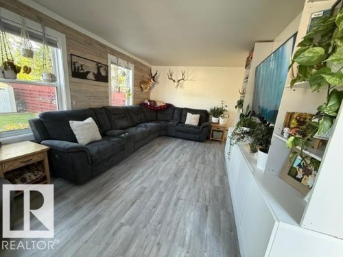 Spacious living area featuring light wood-finish flooring, multiple windows, and a built-in media console with integrated shelving - 4917 45 Avenue, Vegreville, AB - Indoor Photo Showing Living Room