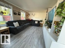 Spacious living area featuring light wood-finish flooring, multiple windows, and a built-in media console with integrated shelving - 