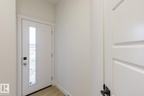 Entryway featuring a contemporary white door with a vertical glass insert, modern silver hardware, and a smart lock system - 6308 65 Avenue, Beaumont, AB 