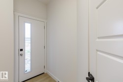 Entryway featuring a contemporary white door with a vertical glass insert, modern silver hardware, and a smart lock system - 