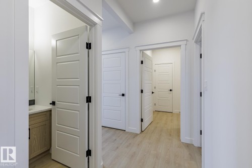 Entryway featuring wood-finish flooring, white paneled doors, matte black hardware, and recessed lighting - 6308 65 Avenue, Beaumont, AB 