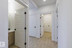 Entryway featuring wood-finish flooring, white paneled doors, matte black hardware, and recessed lighting - 