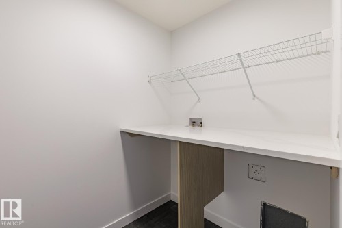 Dedicated laundry area featuring a white countertop, overhead wire shelving, and dark wood-finish flooring - 6308 65 Avenue, Beaumont, AB 