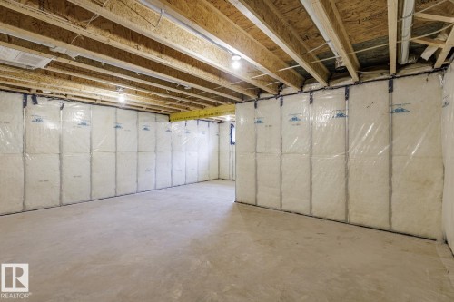 Unfinished basement space featuring exposed wood joists, insulated walls with vapor barrier, and a concrete floor - 6308 65 Avenue, Beaumont, AB 