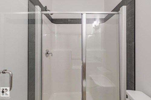 Enclosed shower with clear glass sliding door, integrated shelving, and a built-in bench - 6308 65 Avenue, Beaumont, AB 