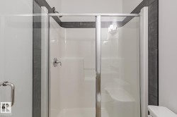 Enclosed shower with clear glass sliding door, integrated shelving, and a built-in bench - 