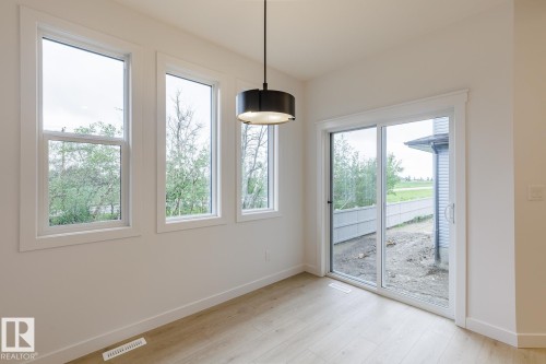 Bright interior space featuring three large windows and a glass sliding door providing ample natural light - 6308 65 Avenue, Beaumont, AB 