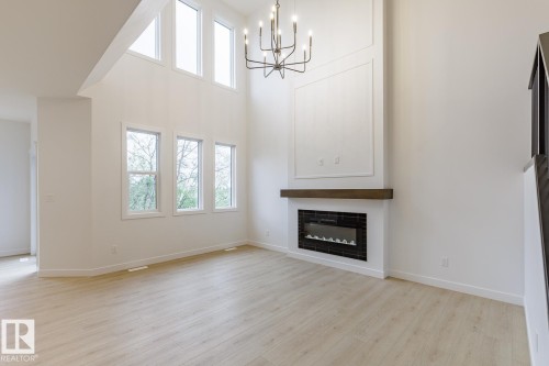 Spacious room featuring soaring ceilings, an elegant chandelier, and wood-finish flooring - 6308 65 Avenue, Beaumont, AB 