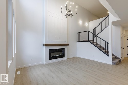 Two-story living area featuring a prominent fireplace with a dark wood-finish mantel and black tile surround - 6308 65 Avenue, Beaumont, AB 
