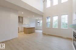 Spacious open-concept living area featuring high ceilings, light wood-finish flooring, and expansive windows - 