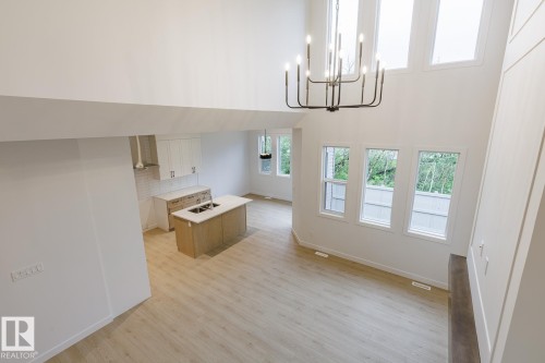 Open-concept living area featuring a vaulted ceiling and a prominent black chandelier - 6308 65 Avenue, Beaumont, AB 