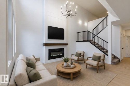 Living room featuring a two-story ceiling, multiple tall windows, and light wood-finish flooring - 6308 65 Avenue, Beaumont, AB 