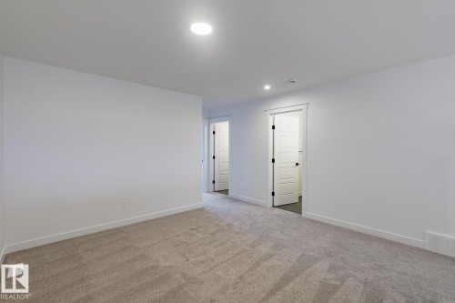 Spacious room featuring neutral carpet flooring, recessed lighting, white walls, and bright white trim - 6308 65 Avenue, Beaumont, AB 