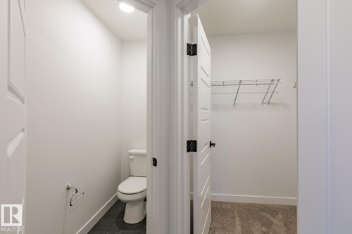 Powder room featuring a white toilet, dark tile flooring, and a chrome towel ring - 6308 65 Avenue, Beaumont, AB 