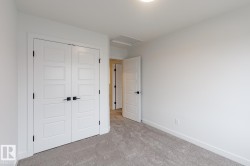 Bedroom featuring light gray carpeting, white walls, white trim, and a white paneled door with black hardware - 