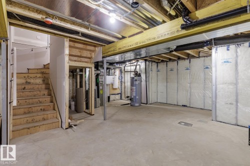 Unfinished basement featuring exposed wood joists, concrete flooring, insulated walls, an accessible water heater, and a visible HVAC system - 6308 65 Avenue, Beaumont, AB 