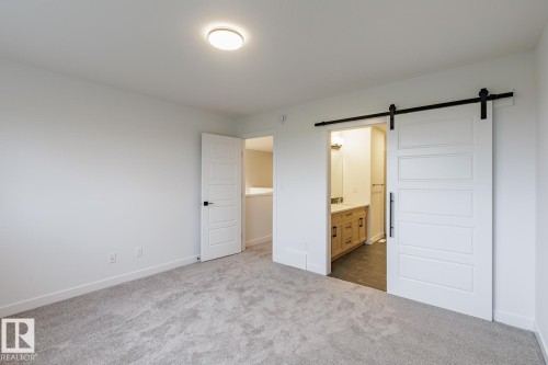 Spacious room featuring light gray carpet flooring and white walls - 6308 65 Avenue, Beaumont, AB 