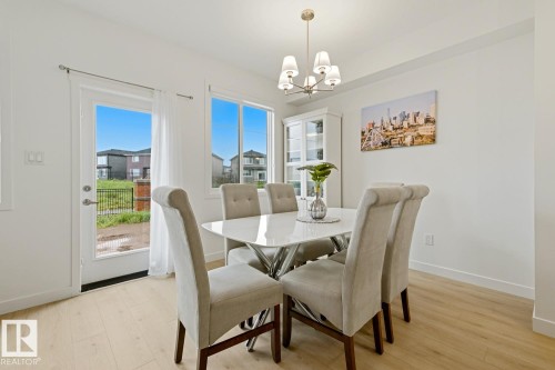 Bright dining area featuring light wood-finish flooring, white walls, and a contemporary chandelier - 22924 82 Ave, Edmonton, AB 
