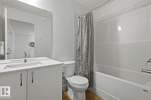 Bathroom featuring a white vanity with an integrated sink, polished chrome faucet, and a large frameless mirror - 22924 82 Ave, Edmonton, AB 