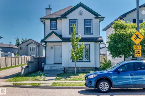 Two-story residence featuring white siding with dark trim, a dark roof, and a chimney - 203 84 Street, Edmonton, AB 