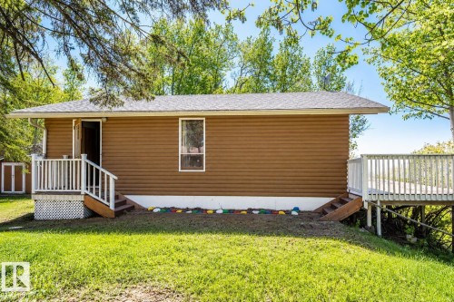 Exterior showcasing brown horizontal siding, a white foundation, and a shingled roof - 27 Point Drive, Rural St. Paul County, AB - Outdoor With Deck Patio Veranda