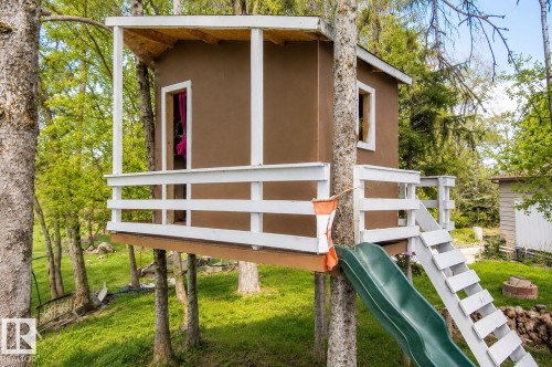 Treehouse structure featuring a brown exterior, white railing, and a green slide - 27 Point Drive, Rural St. Paul County, AB - Outdoor