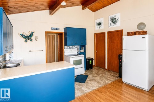 Kitchen area featuring vaulted wood-paneled ceilings, a wood-finish flooring, and a white refrigerator - 27 Point Drive, Rural St. Paul County, AB - Indoor Photo Showing Kitchen