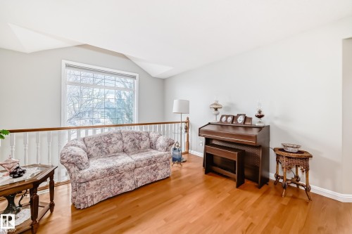 Open concept loft area featuring hardwood flooring, white spindle railing, and a large picture window with grid detailing - 168 Kulawy Drive N, Edmonton, AB 