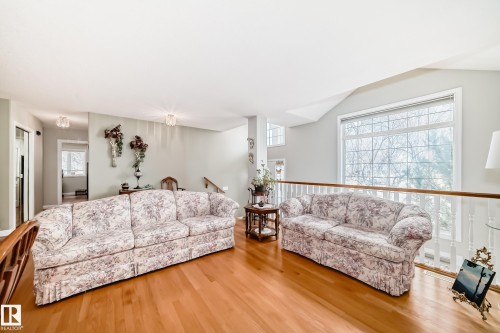 Spacious interior with wood-finish flooring, light-toned walls, and a large grid-pattern window - 168 Kulawy Drive N, Edmonton, AB 