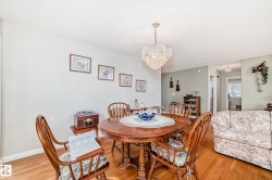 Dining area featuring a prominent chandelier, wood-finish flooring, and light-toned walls - 