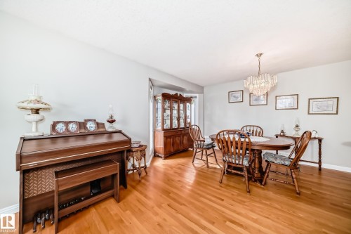Hardwood-finish flooring throughout this room, featuring a built-in display cabinet and a crystal chandelier - 168 Kulawy Drive N, Edmonton, AB 