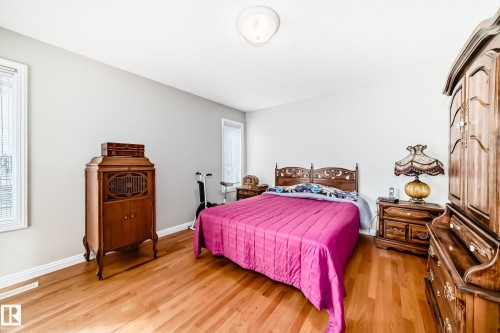 Bright bedroom featuring warm wood-finish flooring and neutral wall tones - 168 Kulawy Drive N, Edmonton, AB 
