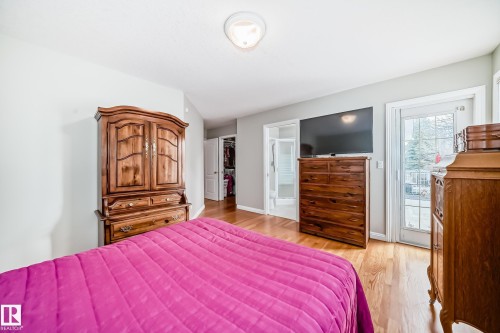Hardwood flooring throughout, featuring a glass-paned door, light gray wall paint, and a ceiling-mounted light fixture - 168 Kulawy Drive N, Edmonton, AB 