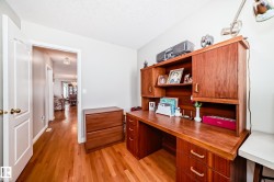 Hardwood flooring throughout this versatile room, featuring a built-in wood-finish desk with integrated shelving and cabinetry - 
