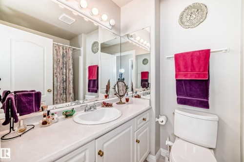 Bathroom with an integrated sink, vanity with cabinet storage, and a large wall-mounted mirror - 168 Kulawy Drive N, Edmonton, AB 