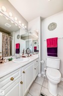 Bathroom featuring a white vanity with extensive storage, a large integrated mirror, and overhead vanity lighting - 