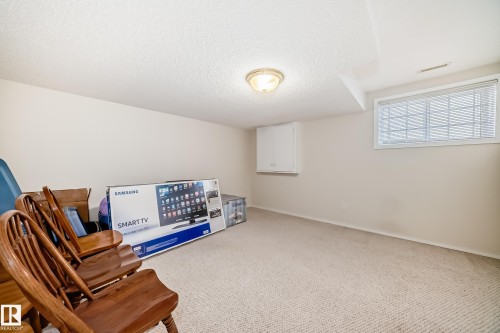 Carpeted room featuring a ceiling-mounted light fixture and a single window with blinds - 168 Kulawy Drive N, Edmonton, AB 
