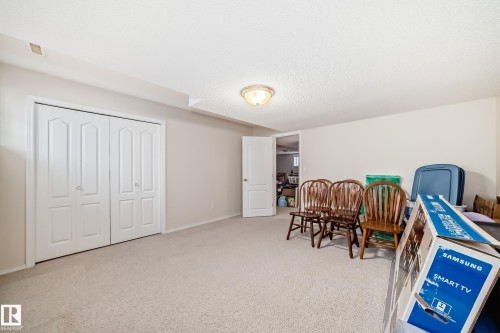 Carpeted room featuring white bi-fold closet doors, light-toned walls, a white ceiling, and a flush-mount ceiling light fixture - 168 Kulawy Drive N, Edmonton, AB 