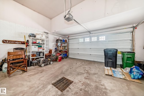 Garage interior featuring a concrete floor, white overhead garage door with window inserts, and an automatic garage door opener - 168 Kulawy Drive N, Edmonton, AB 