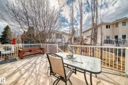 Expansive concrete patio featuring white railing, mature trees, and a beige stucco exterior - 