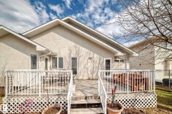 Rear exterior featuring a multi-level wood deck with white railing, stucco siding, and a partial grass lawn - 