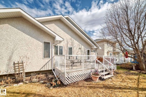 Rear exterior showcasing a raised wooden deck with white railing, stucco siding, and multiple windows - 168 Kulawy Drive N, Edmonton, AB 