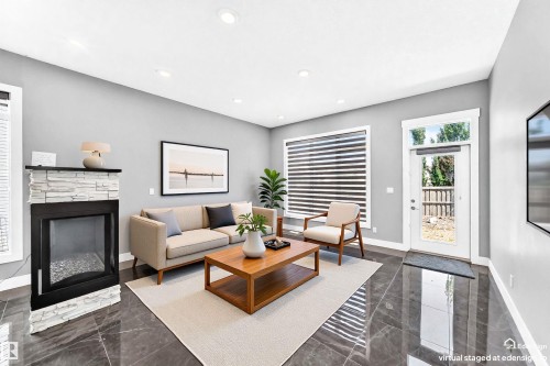 Living area featuring polished stone-look flooring, a fireplace with a stacked stone facade, recessed ceiling lighting, and a glass-paneled exterior door - 1781 Melrose Crescent, Edmonton, AB 
