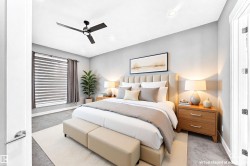 Spacious bedroom featuring light gray walls, carpet flooring, a modern ceiling fan, and recessed lighting - 