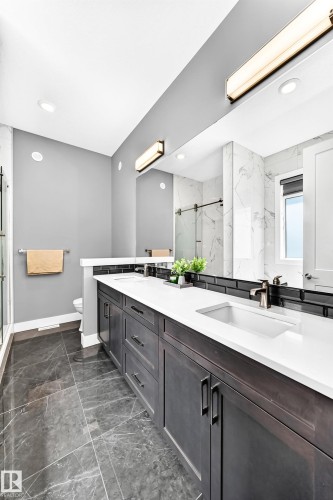 Double vanity with white countertops, dark wood-finish cabinetry, and contemporary bronze fixtures - 1781 Melrose Crescent, Edmonton, AB 