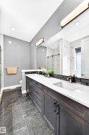 Double vanity with white countertops, dark wood-finish cabinetry, and contemporary bronze fixtures - 