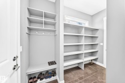 Mudroom featuring built-in shelving, a bench with shoe storage, and coat hooks - 