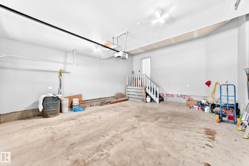 Spacious interior garage featuring a concrete floor, light gray walls, and an interior staircase leading to an upper level - 1781 Melrose Crescent, Edmonton, AB 