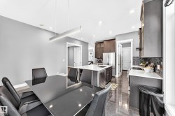 Spacious dining area featuring a modern linear pendant light and a sleek black table - 
